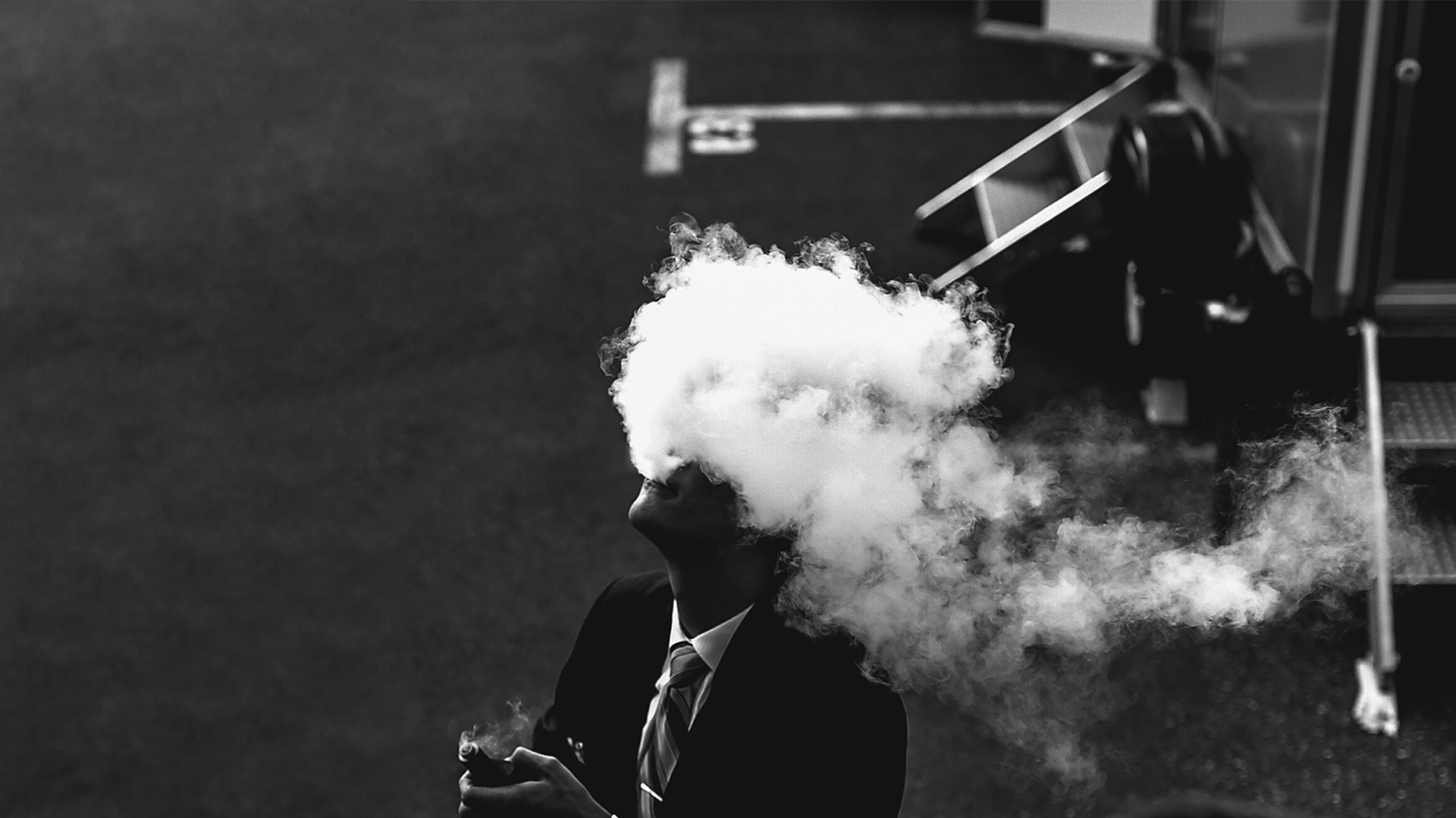 A student in school uniform vaping with an e-cigarette, in black and white